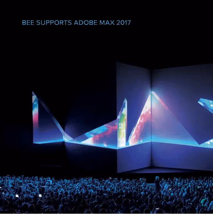 Adobe Max support stage: Dark stage backdrop reading “BEE SUPPORTS ADOBE MAX 2017,” with angular white panels and blue-purple light projections.