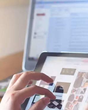 Person browsing visual content on tablet with email inbox open on laptop in background, representing choosing the right email layout.