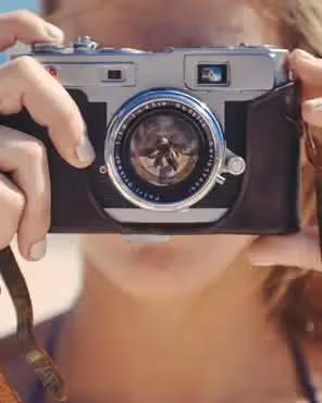 Abstract illustration of cameras, light bulbs, and creative tools on a gradient background, symbolizing using stock photos in email.
