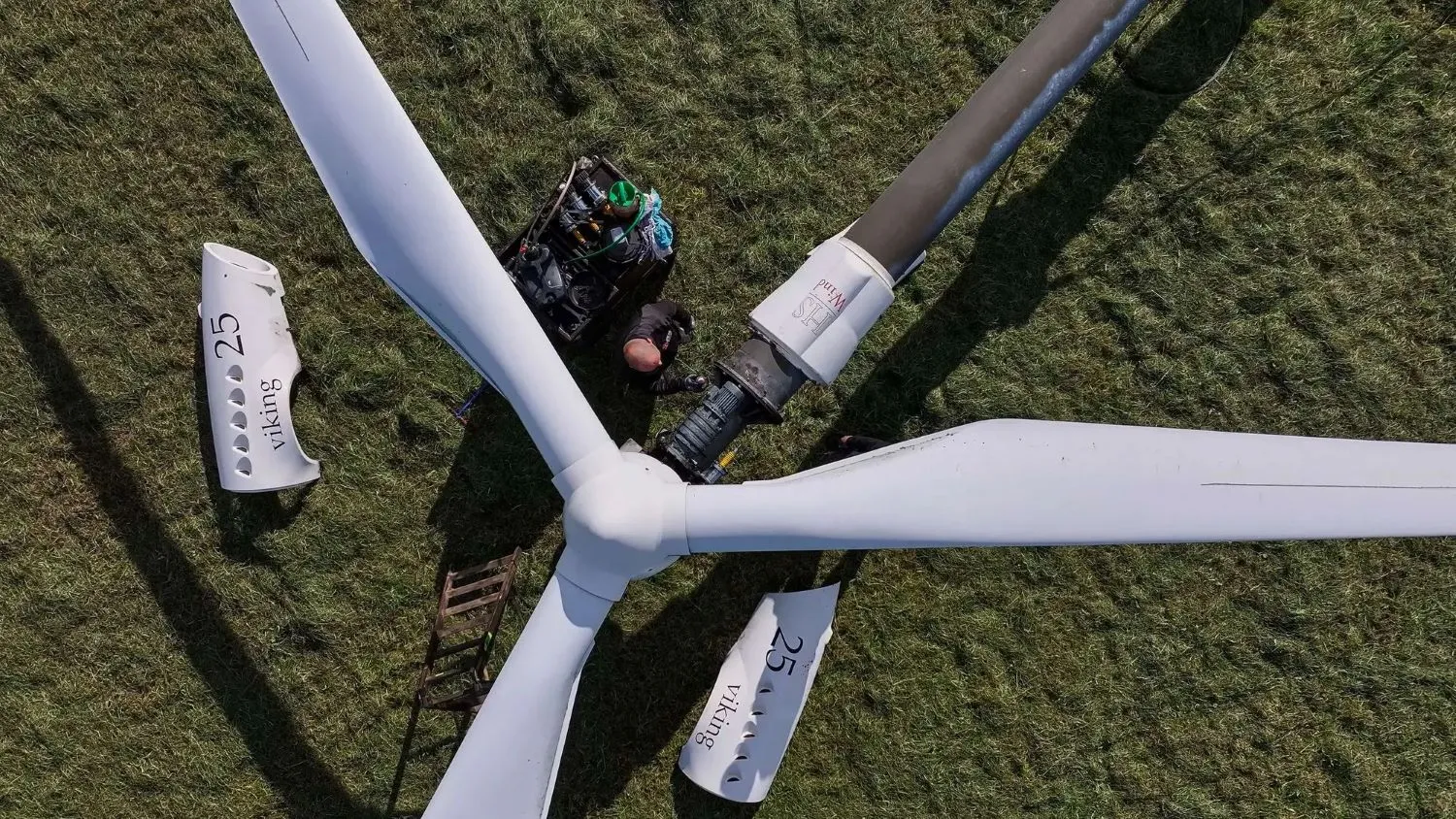 Closeup af et hoved på en vindmølle, der ligger ned og bliver repareret af en mand