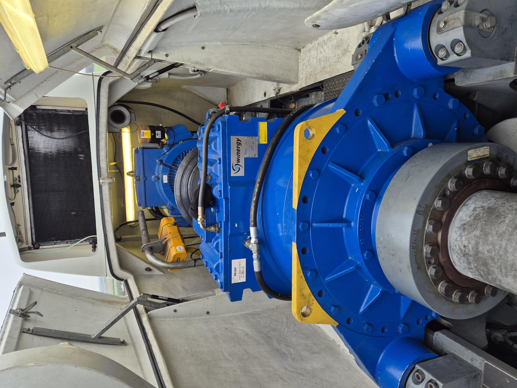 Close-up view inside a wind turbine nacelle showing blue mechanical components and a large shaft, labeled with Winergy logos.