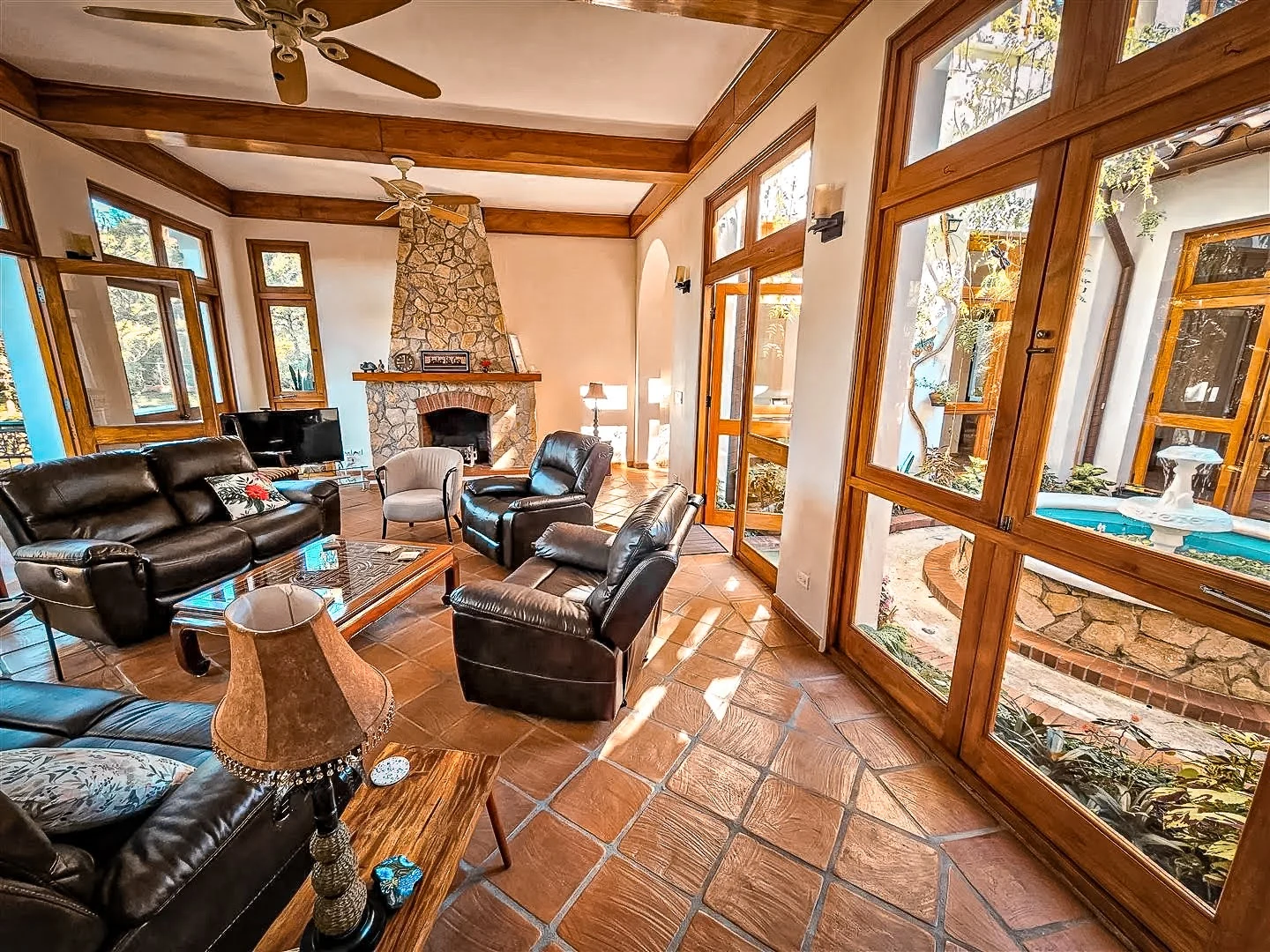 Comfortable common living area overlooking Serenity Vista's tranquil atrium with koi pond, fountain, abundant natural light, and solid teak wood craftsmanship in our private luxury rehab in Boquete, Panama.