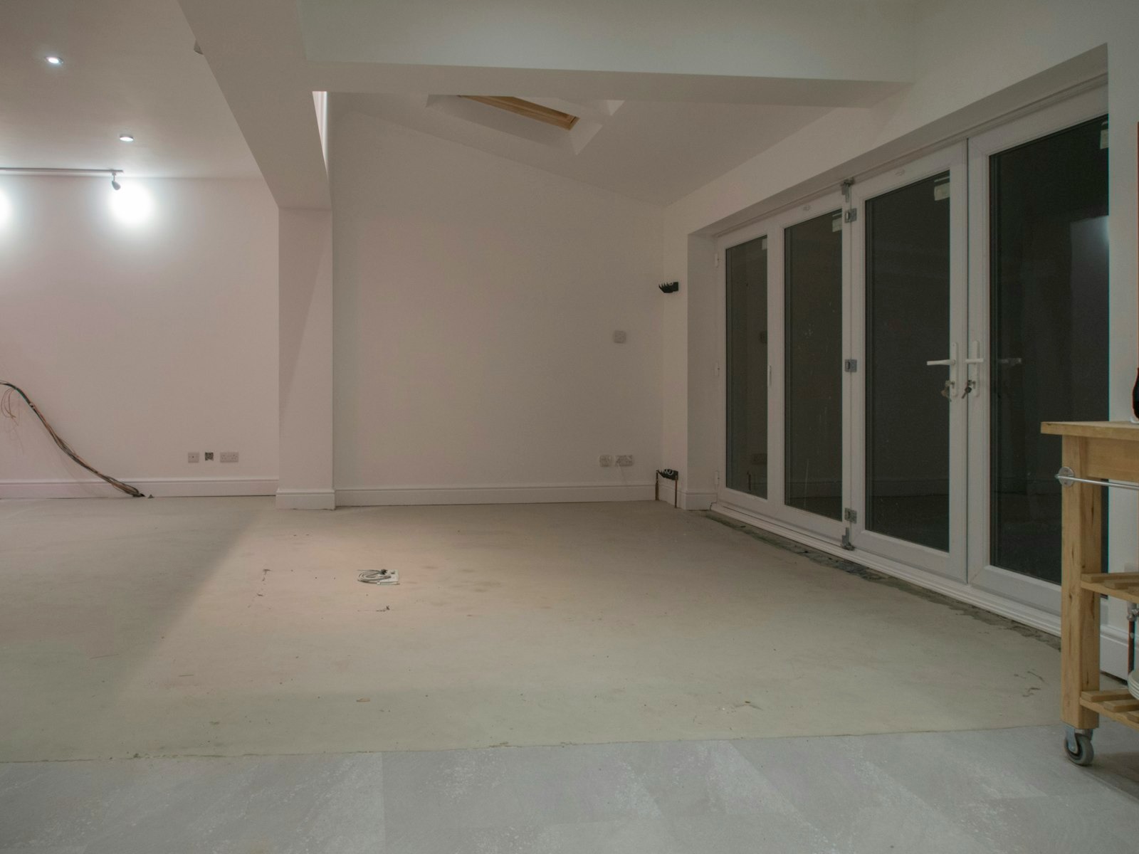 Ruangan kosong berdinding putih dengan pintu kaca setelah tahap bongkar, bagian dari renovasi interior apartemen
