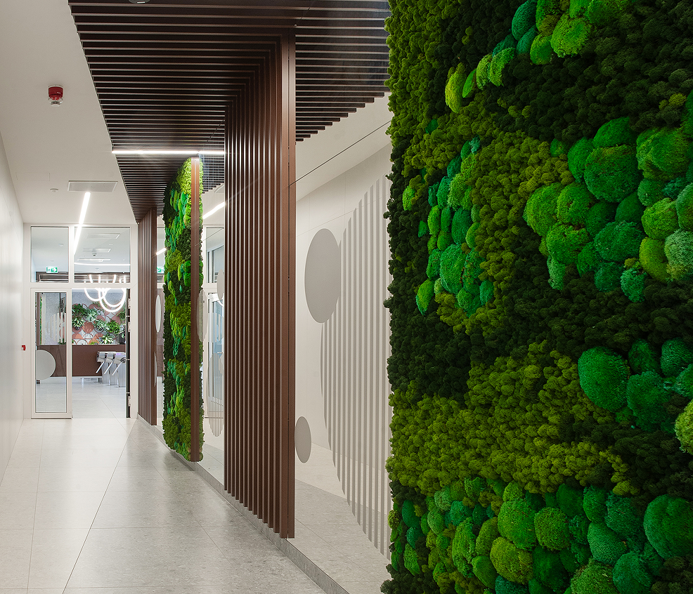 Corridor lined with wooden slats and a moss wall leading towards the lobby