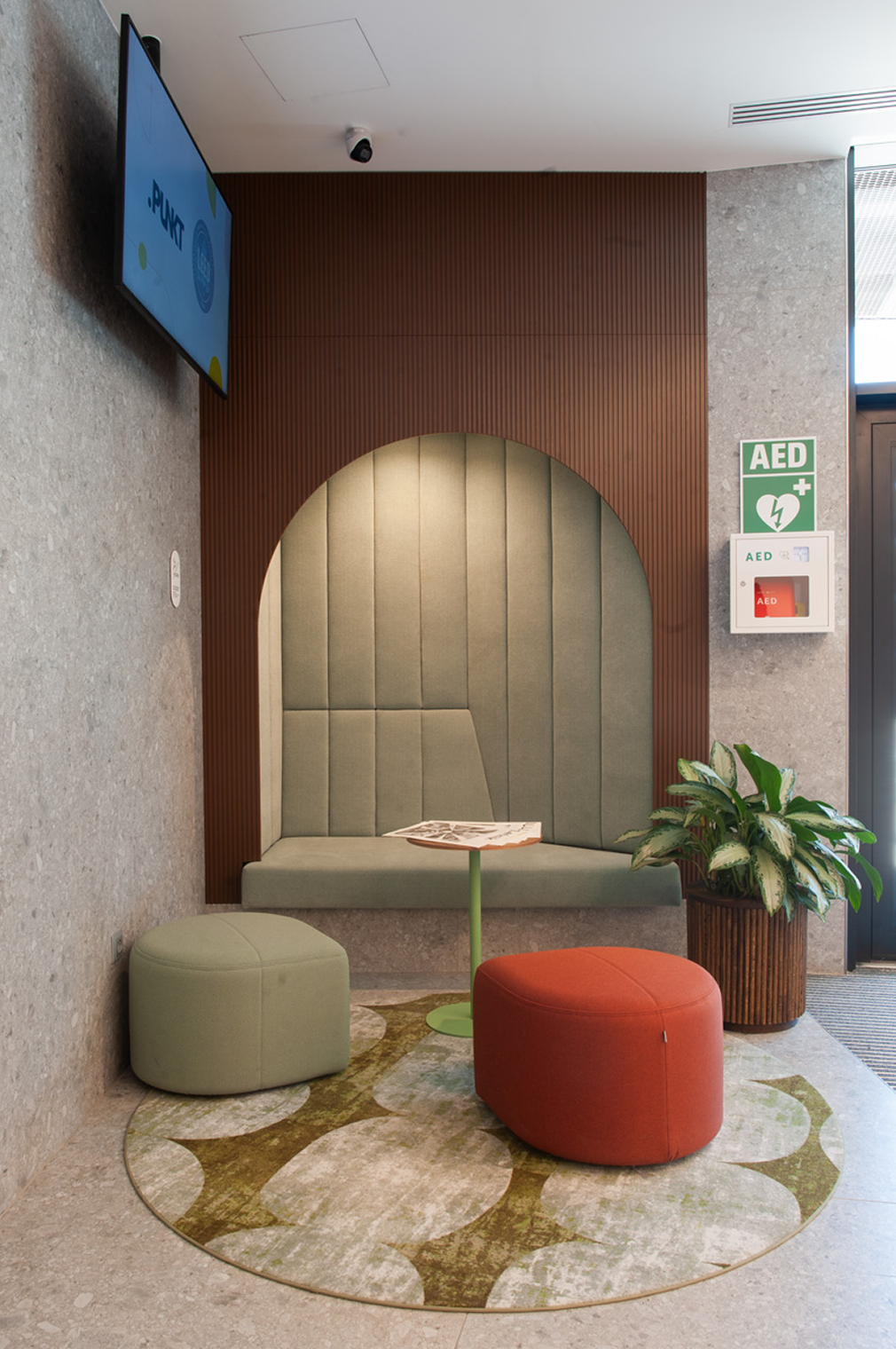 Upholstered seating niche with pouffes and a round rug in the lobby rest zone