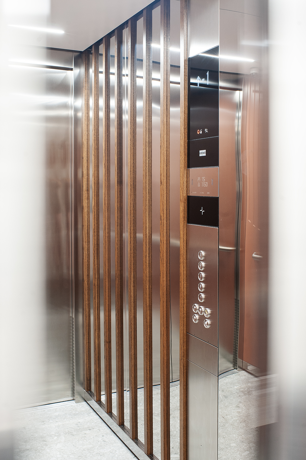 Elevator lobby with wooden slats and a stainless steel call panel