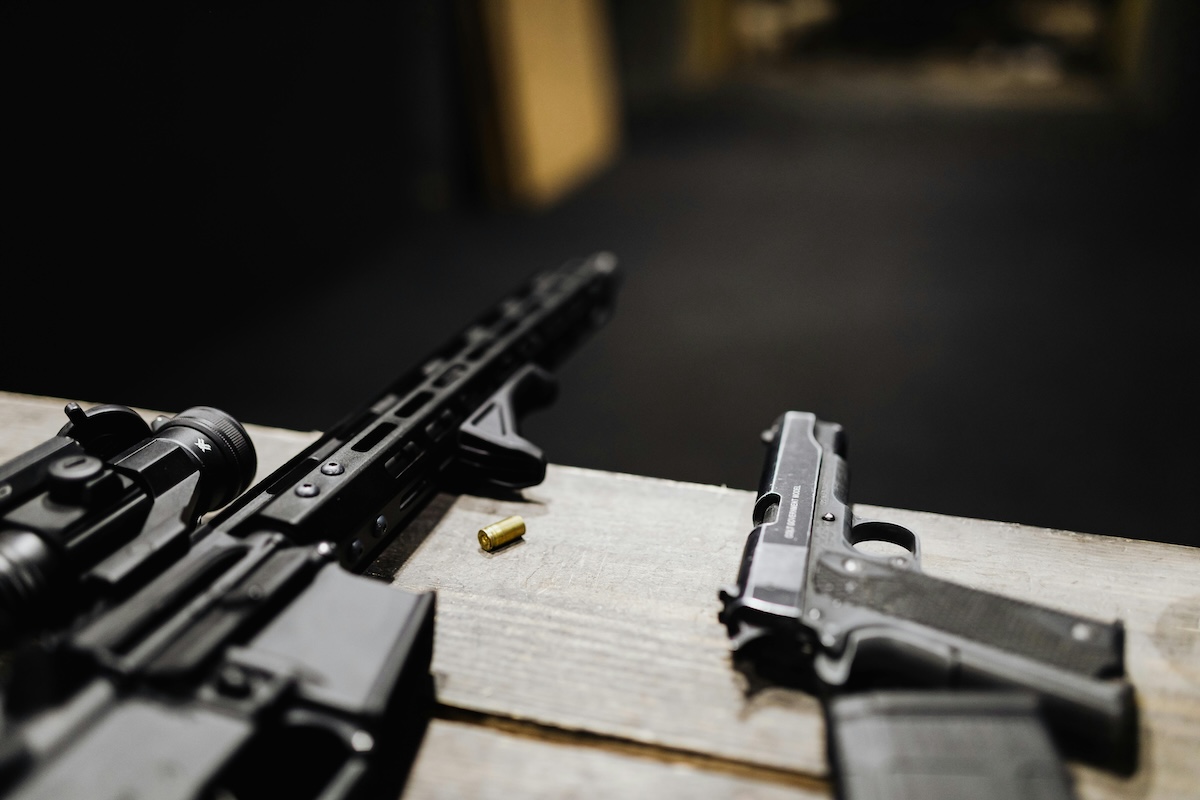 A rifle and a handgun on the counter of shooting range behind a gun shop.