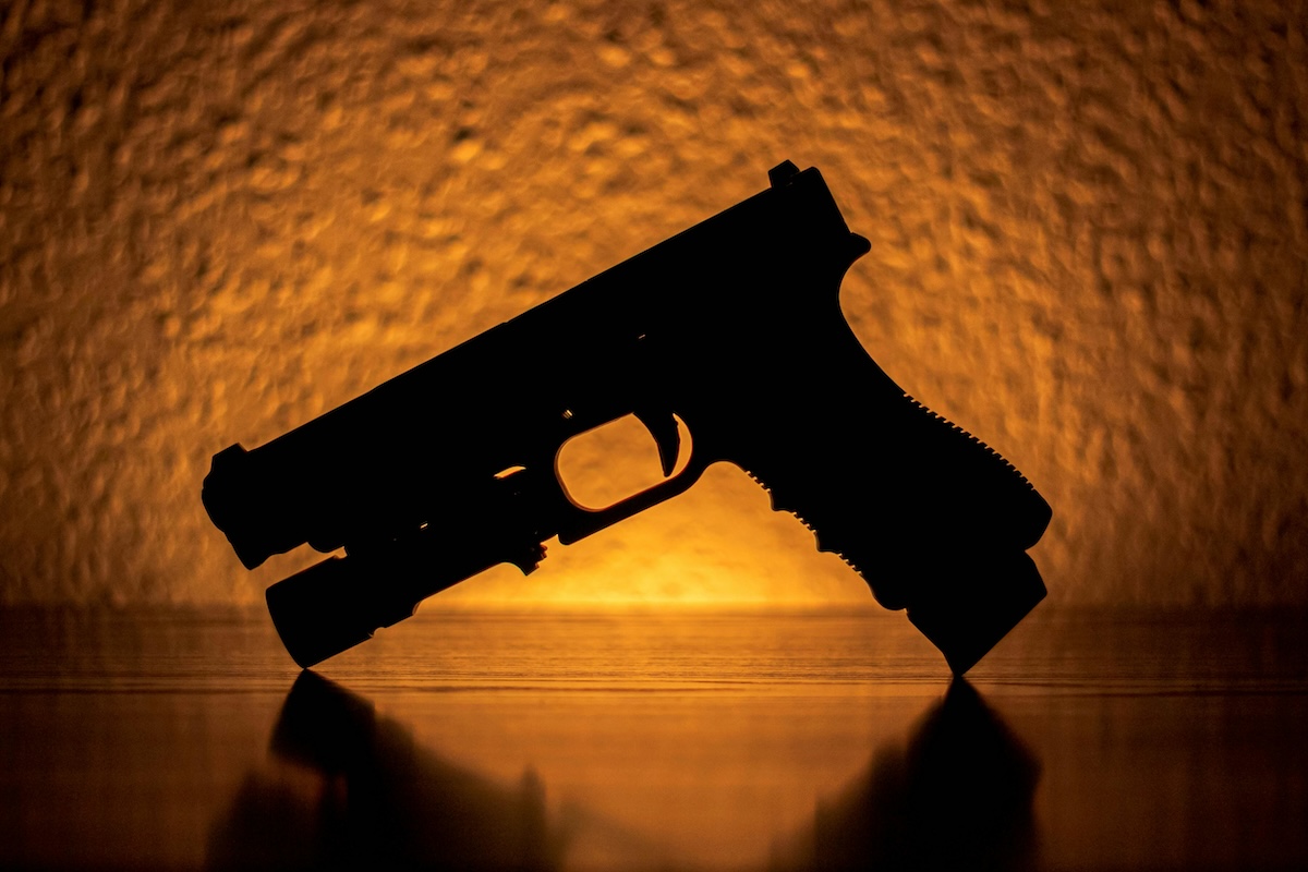 Silhouette of a Pistol Near an Orange Light More info Share