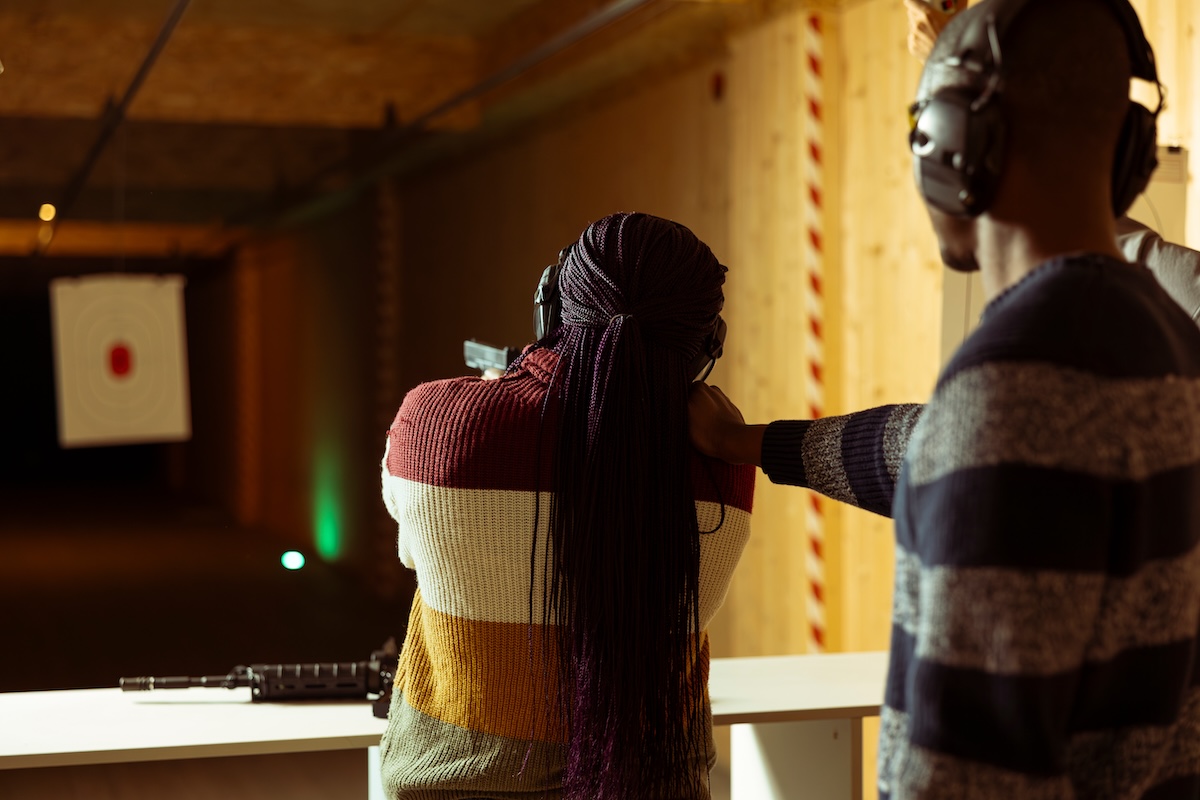 Gun range employee instructs a student on the range with a weapon.