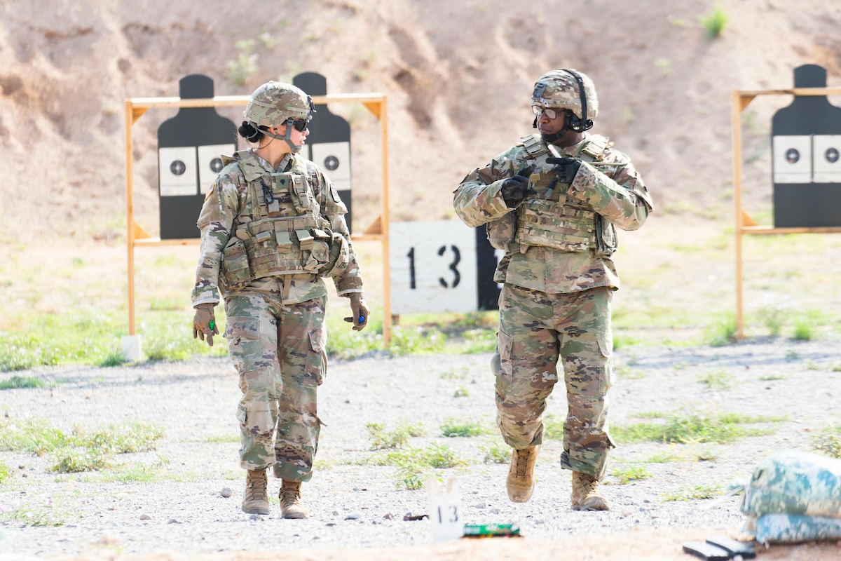 A Man and a Woman in Camouflage Uniform Standing on Ground More info Share