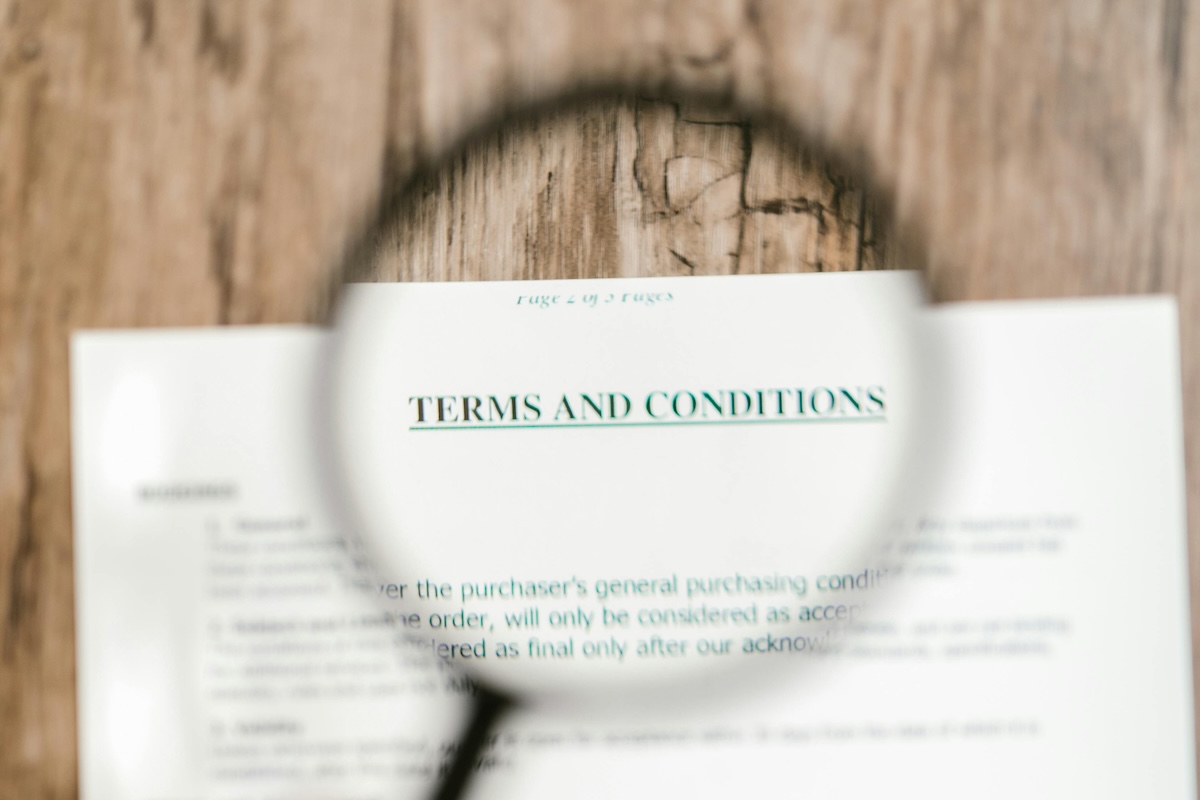 A vendor contract with the words "Terms & Conditions" under a magnifying glass.