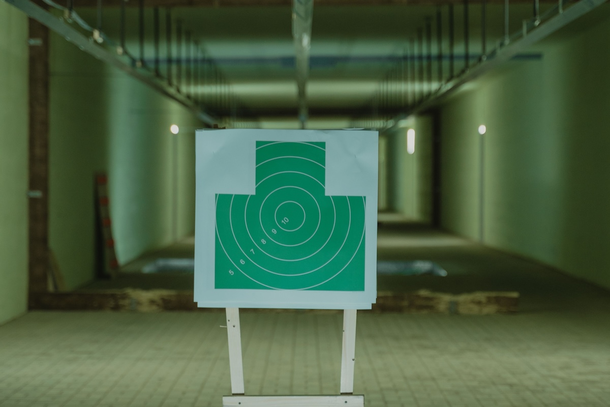 Green shooting target in an indoor range setting, with perspective focus down the range lanes.