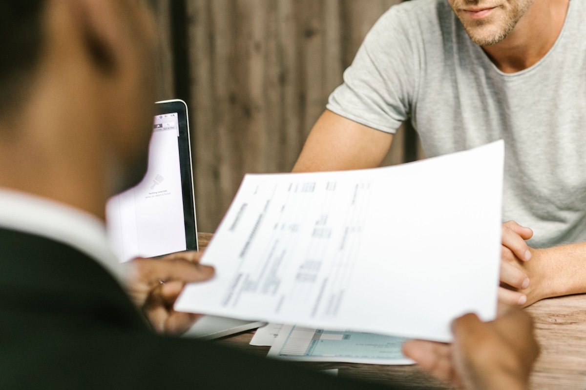 Two men in discussion over documents during a business meeting in a contemporary office setting.