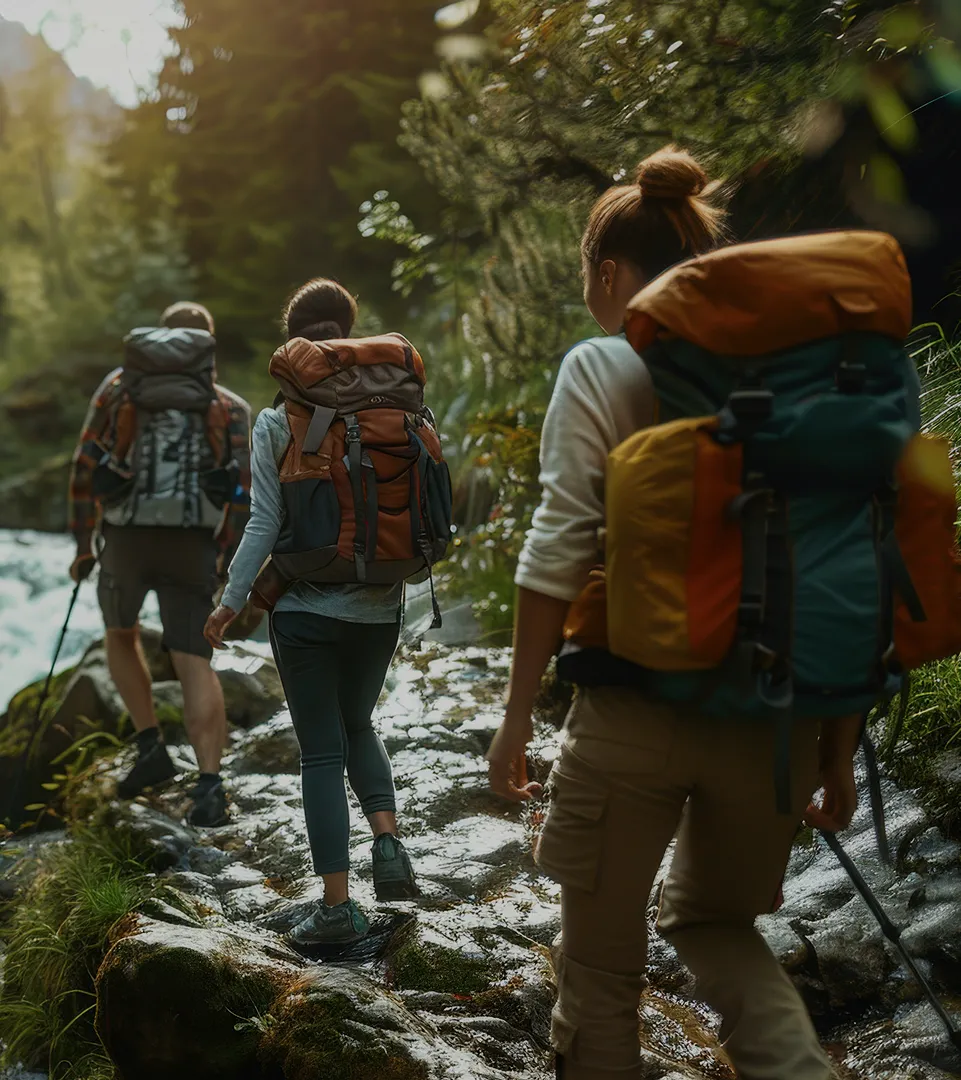 Hikers with backpacks crossing a mountain stream