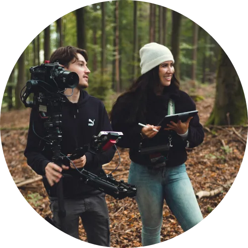 Kira und Niklas halten eine Kamera in der Hand.