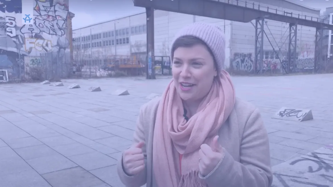 Foto einer Person im Winter die vor einem Industriegelände steht. 
