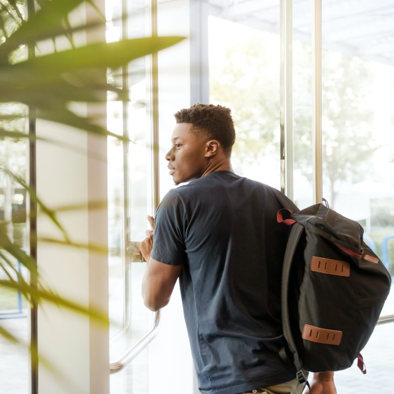 Young black male walking trough glass door