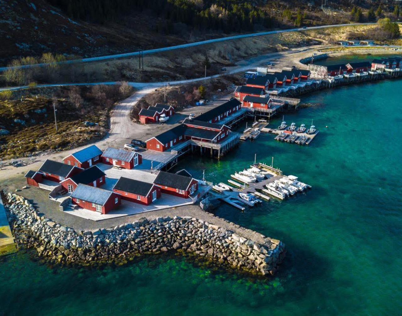 Aerial view of red cabins and fishing boats at Lofoten Havfiske’s base, ideal for fishing trips in Lofoten.