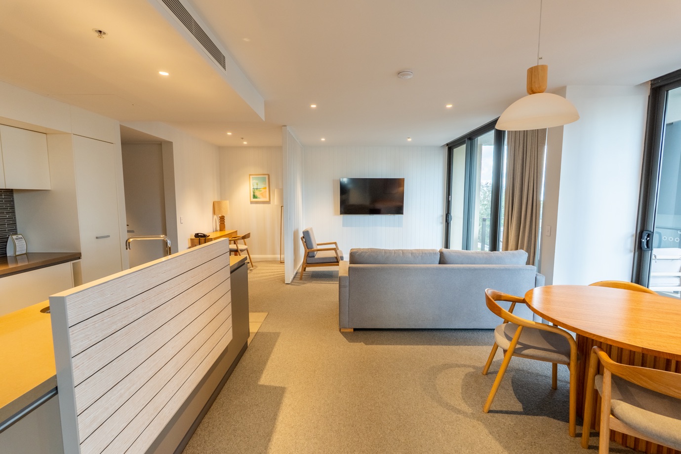 Open-plan living, dining and kitchen area in an Oaks Redcliffe Mon Komo suite