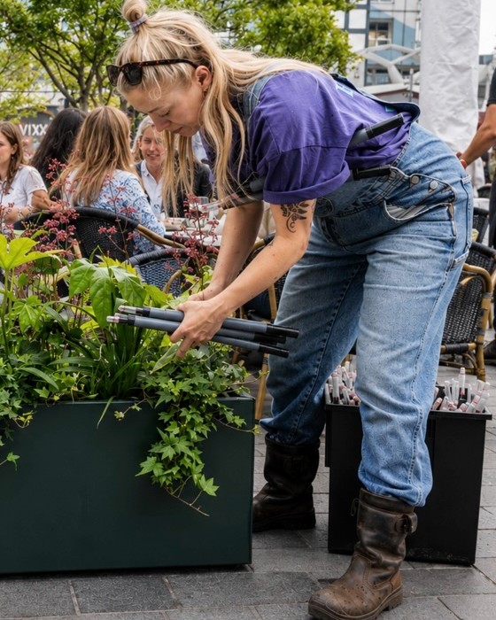 Medewerker van Upperbloom vult een terrasplantenbak met seizoensbeplanting