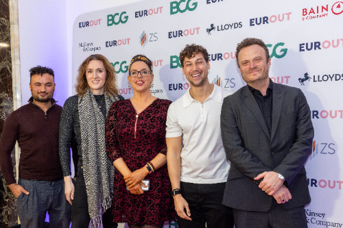 Speakers in front of the EUROUT 2025 sponsor wall