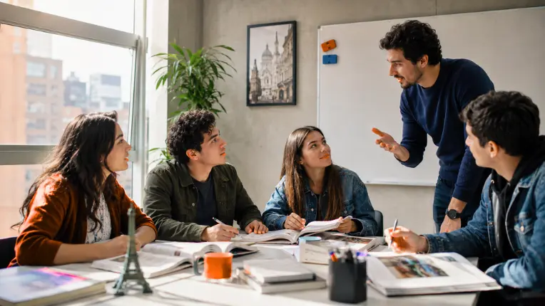 Profesor explicando a sus alumnos en un aula iluminada, referente a cursos de francés en Bogotá y sus opciones de precios.