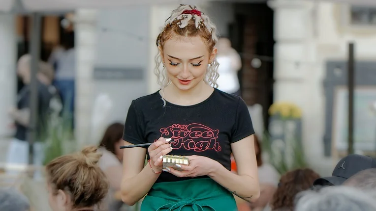 Mesera tomando nota en una libreta en un restaurante, ideal para aprender a cómo pedir comida en inglés.