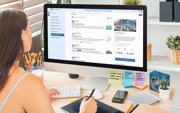 Person working at a desk with a large computer monitor displaying an online discussion forum, holding a stylus with a graphic tablet, surrounded by stationery and sticky notes.