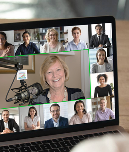 Laptop screen showing a virtual meeting with twelve diverse participants, including a smiling woman in front of a microphone.