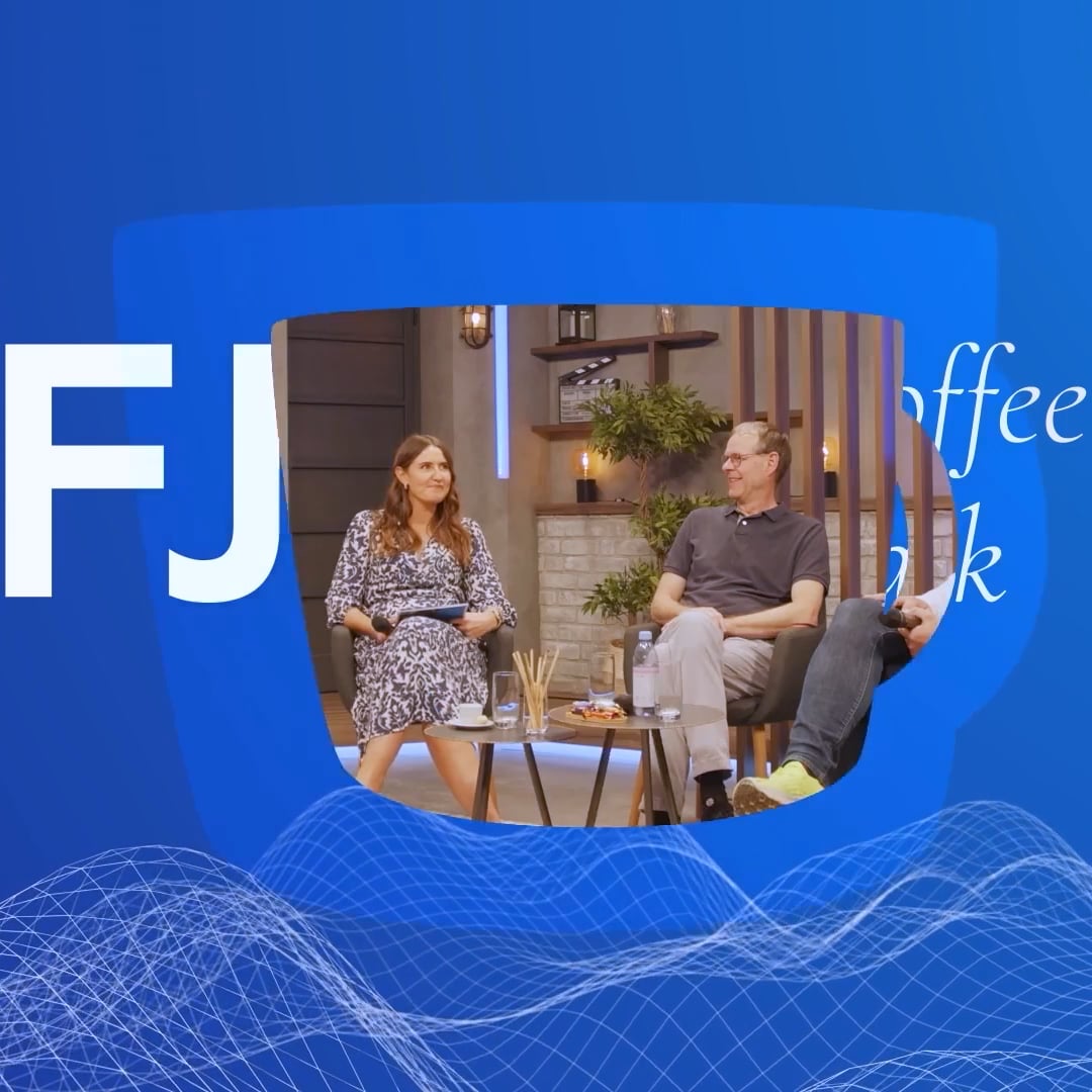 Zwei Personen sitzen auf Sesseln bei einer informellen Gesprächsrunde in einem gemütlichen Studio mit Dekoration und einem kleinen Tisch mit Getränken.