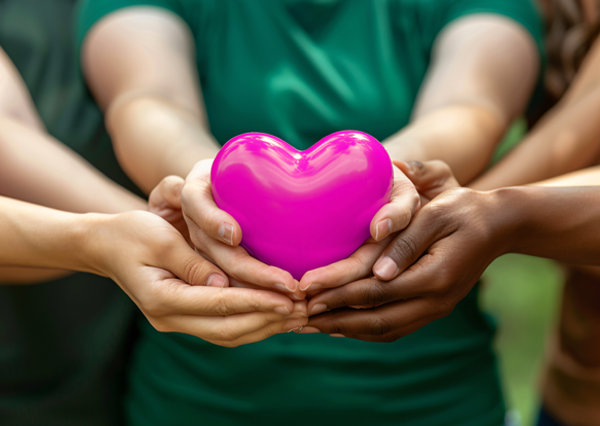 A group of people hold a pink Ambasco heart together.
