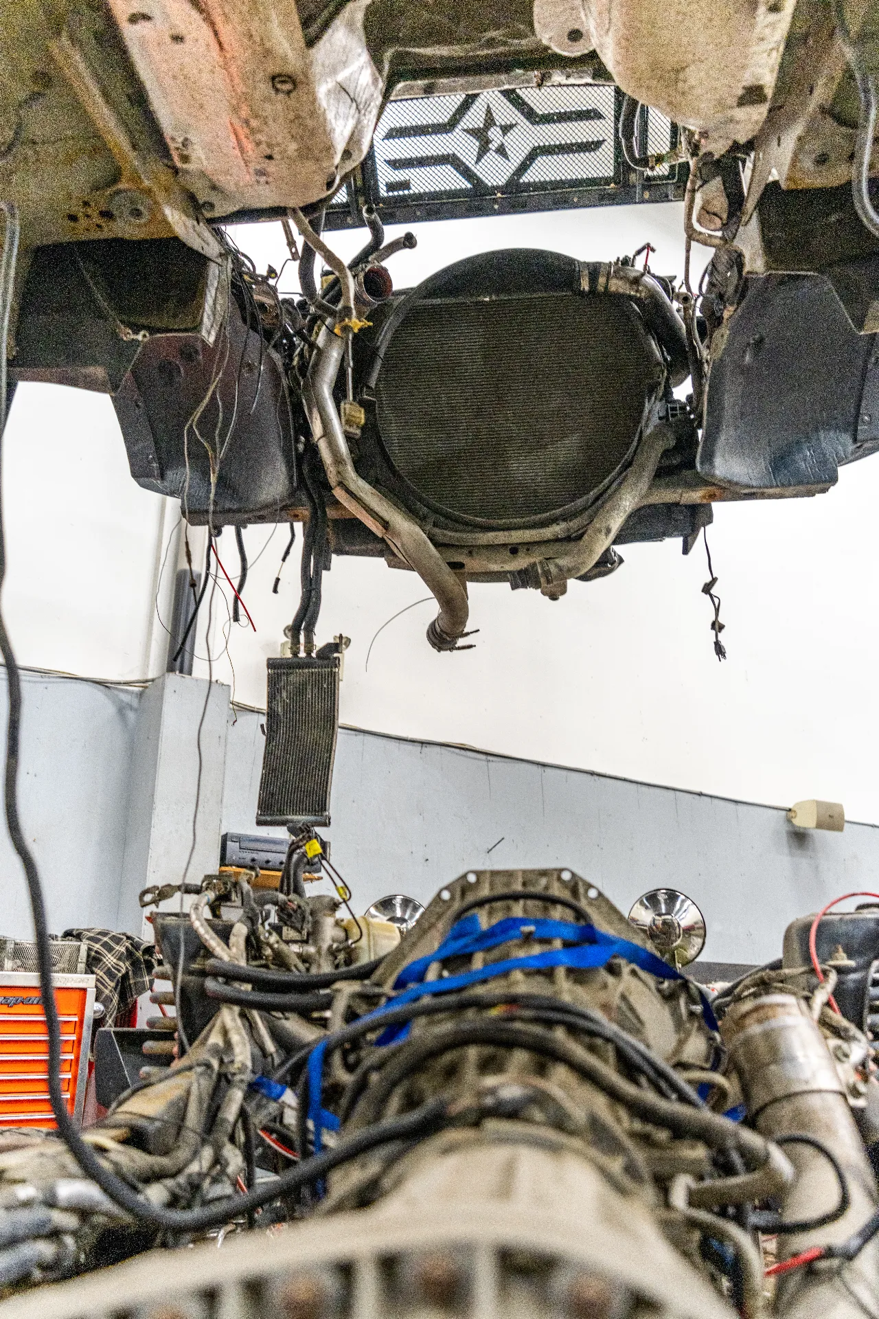 Engine removal in progress showing exposed radiator and transmission aligned below the chassis.