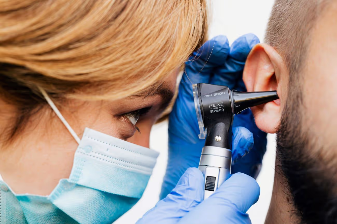 Ärztin untersucht Ohr des Patienten