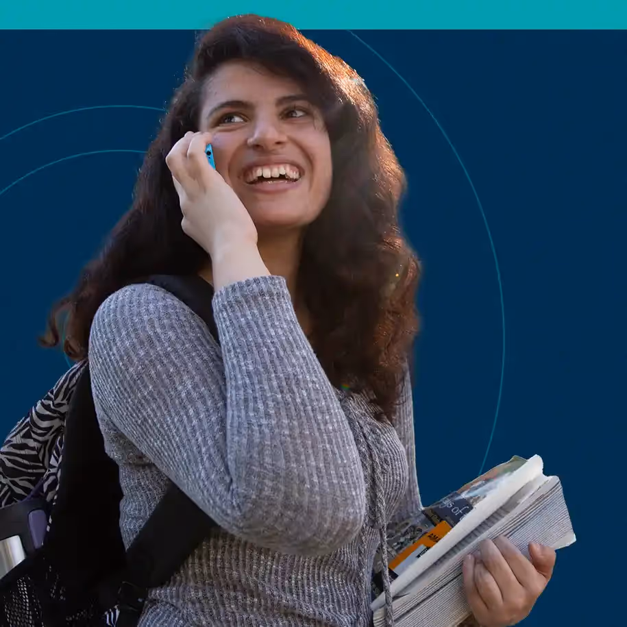 College student holding books and on phone