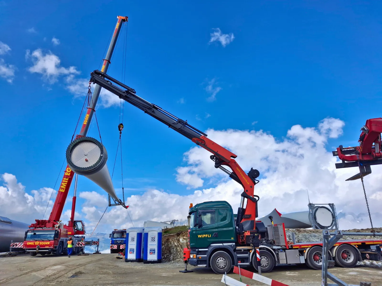 Lastwagen LKW Chauffeur welche mit einem Kran ein Windkraftwerk installieren.
