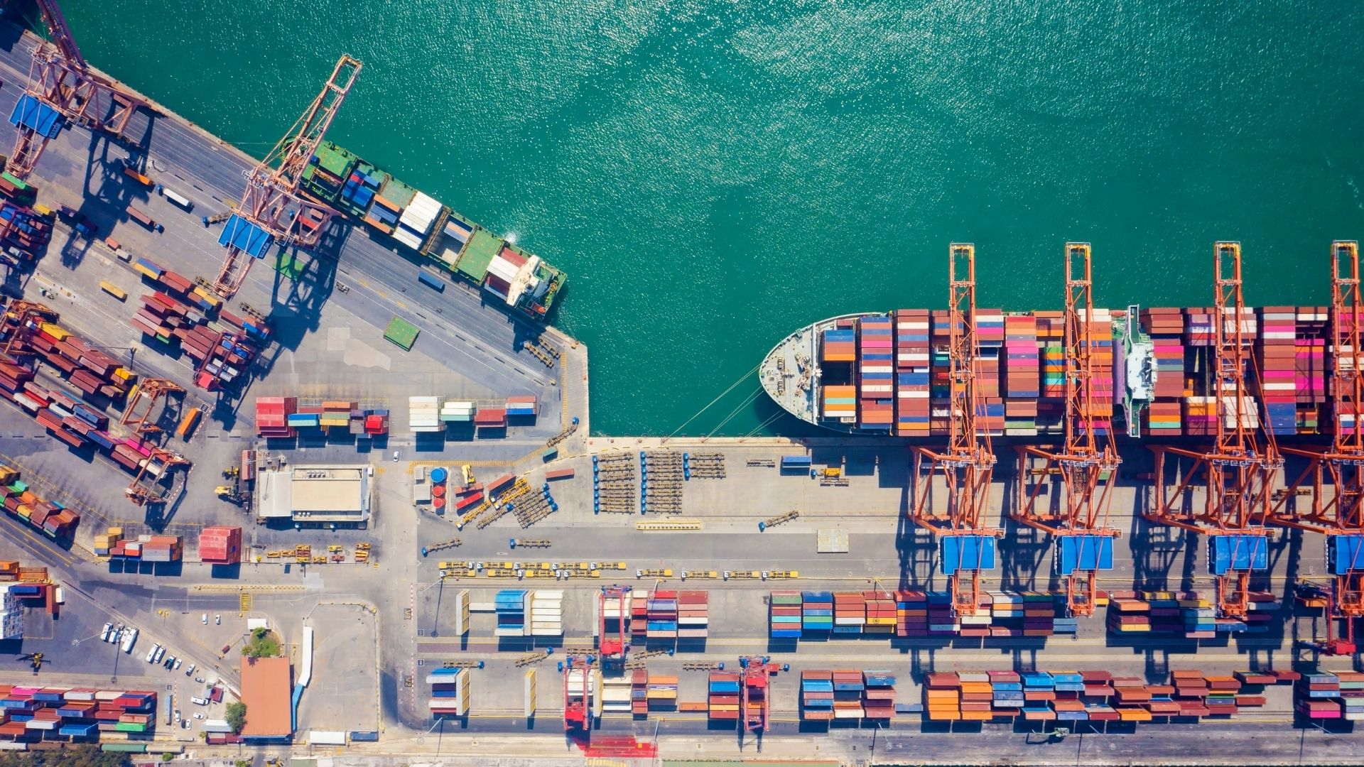 An aerial or top down view of a container ship docked at a port on time ETA