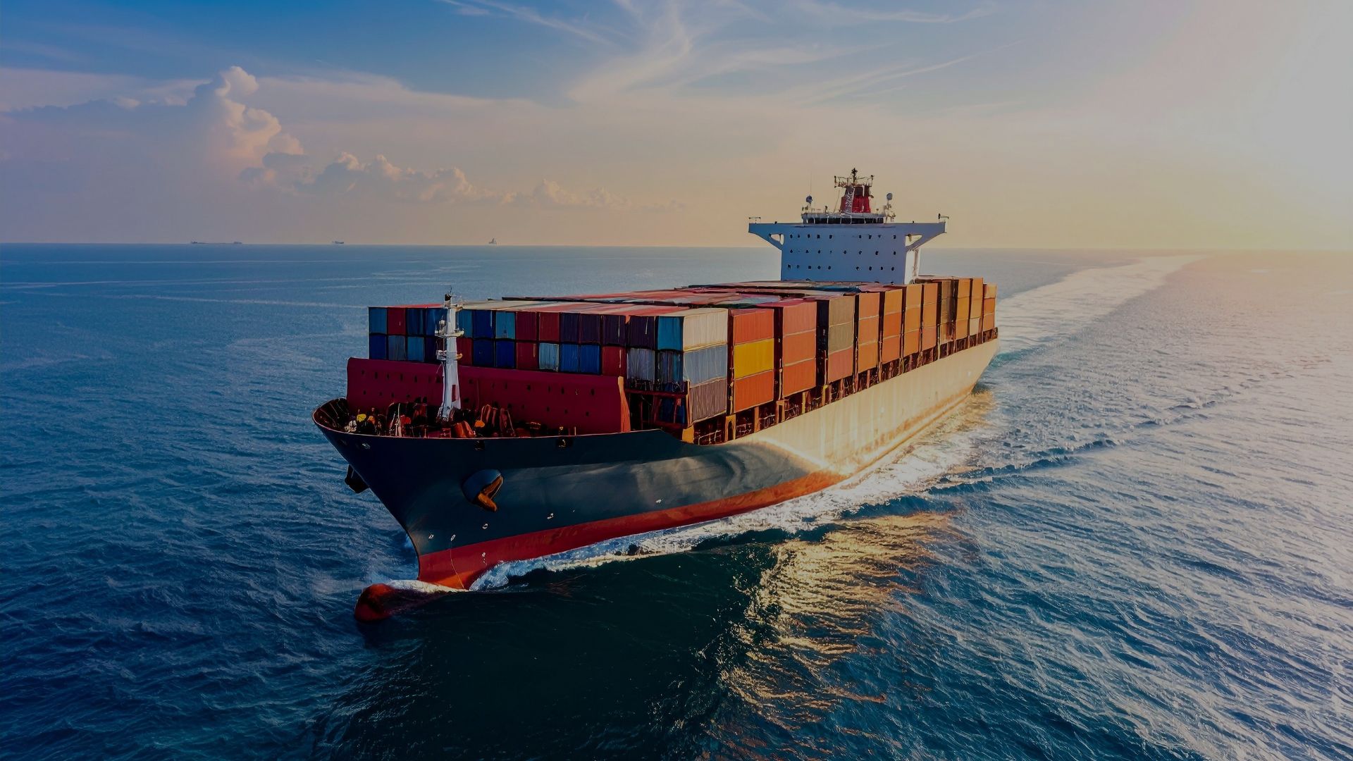 A large freight vessel stacked with multiple containers, moving steadily through the sea