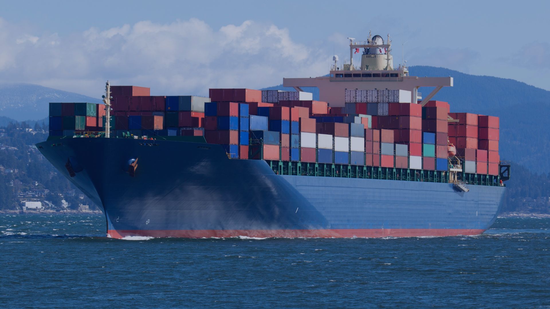 A container ship stacked with shipping containers of different color moving on the the ocean