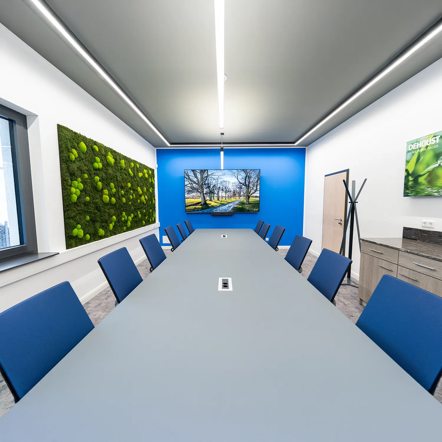 Konferezraum mit Wandbegrünung, grauer Tisch, blaue Stühle, Bürocontaineranlage