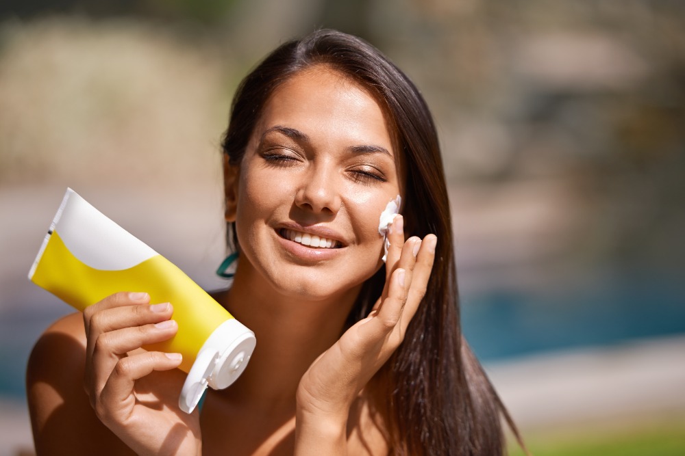 Woman applying sunscreen to protect skin after anti-wrinkle injections and aesthetic enhancements at AL Aesthetics in the UK