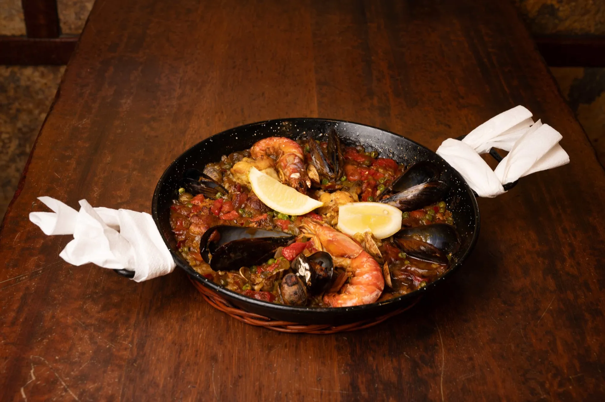 Paella de marisco sobre mesa de madera en Bodega Joan, Barcelona