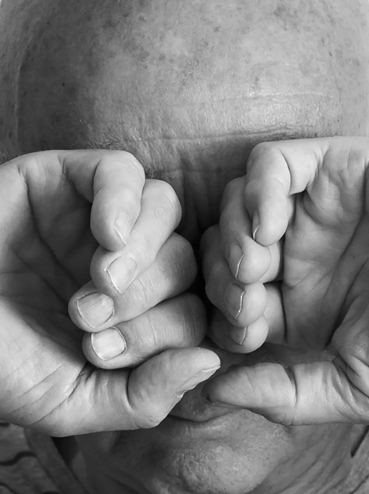 Der Künstler formt beide Hände zu kleinen, fest zusammengedrückten Fäusten und hält sie direkt vor die Augen.