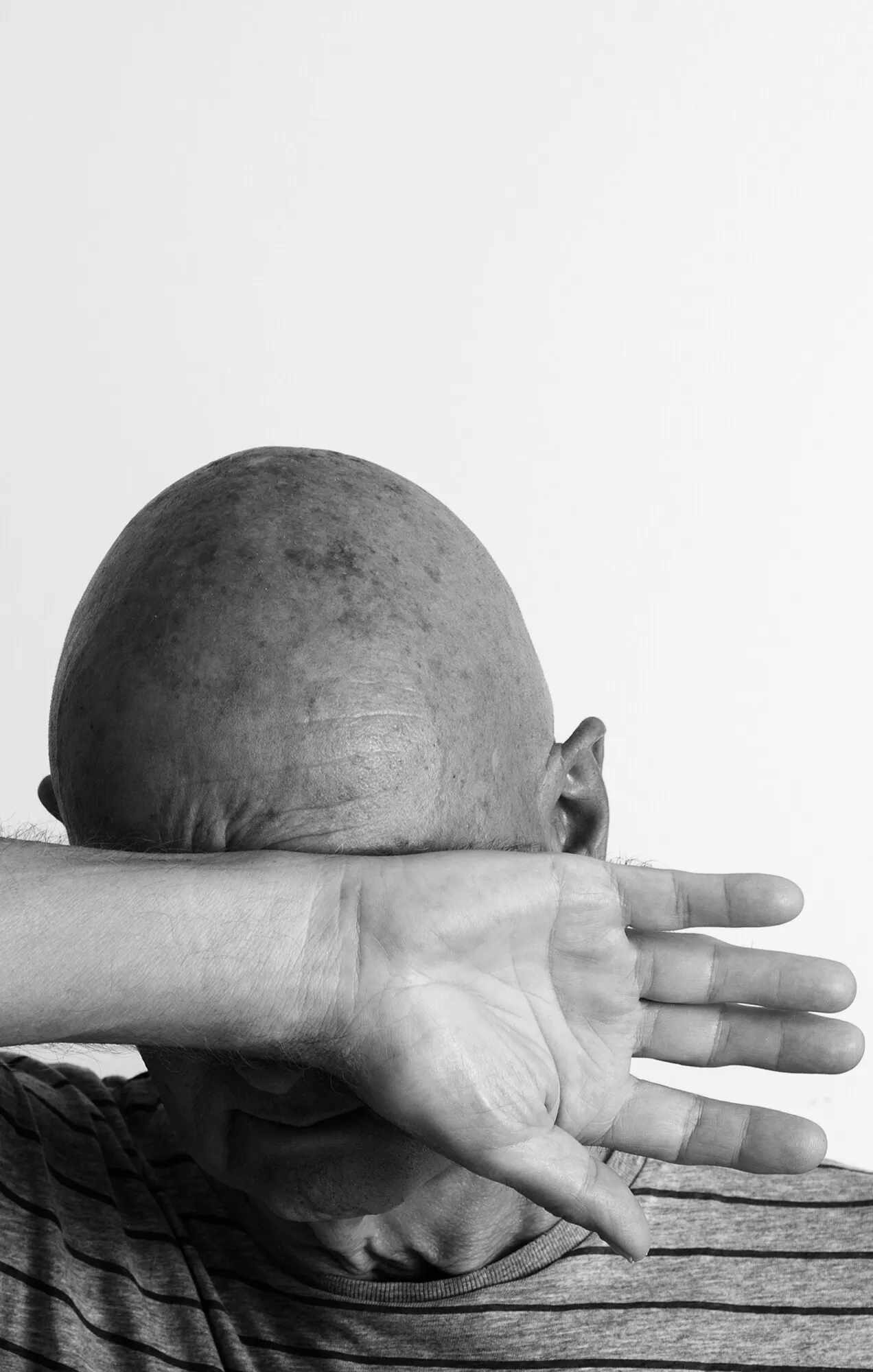 Marcel Peltier – Werkserie „Darkness“ (2022): Der Künstler verdeckt sein Gesicht mit dem horizontal vor Augen und Nase gehaltenen Unterarm