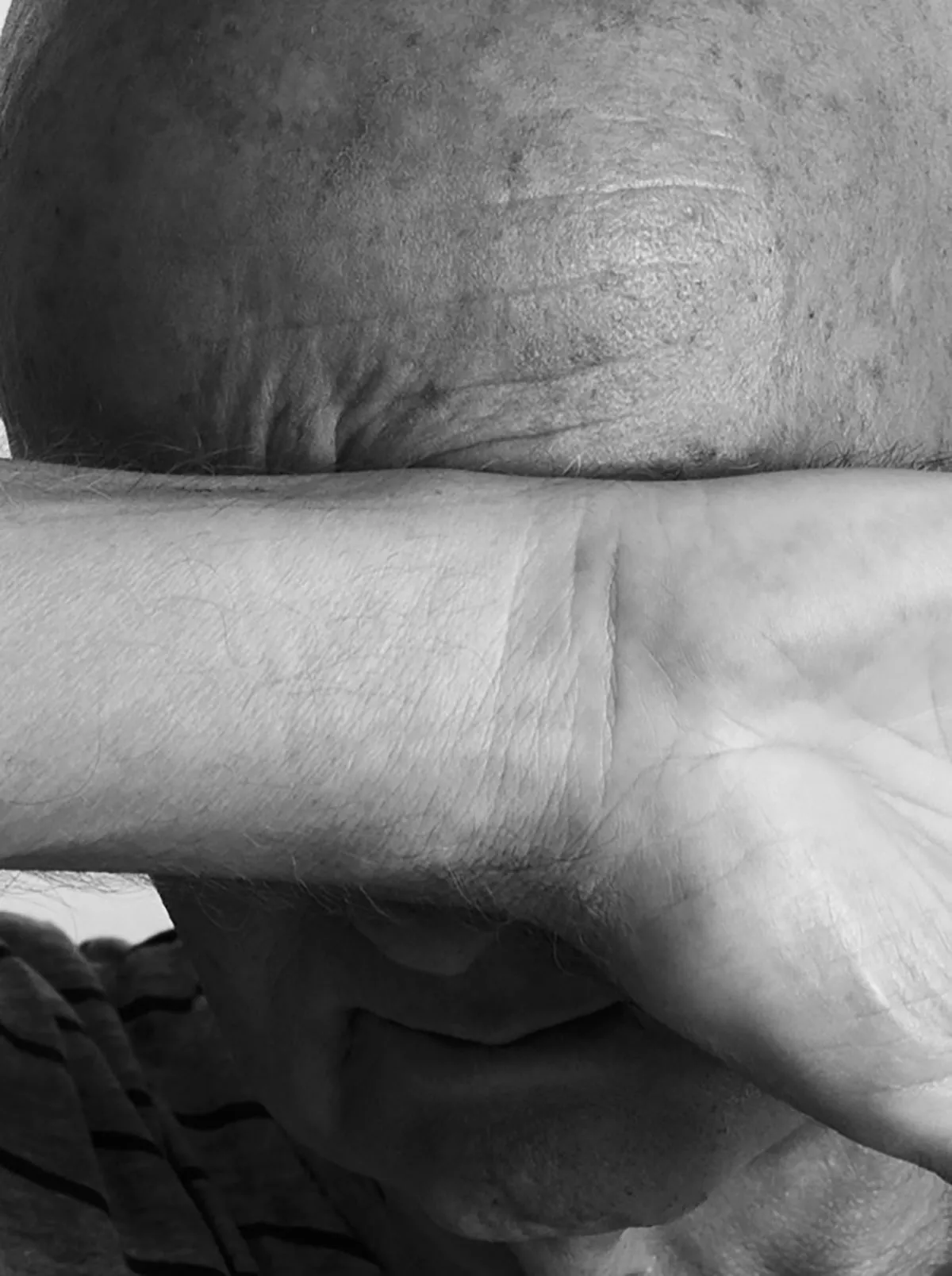 Marcel Peltier – Werkserie „Darkness“ (2022): Der Künstler verdeckt Stirn und Augen mit dem quer über das Gesicht gelegten Unterarm.“