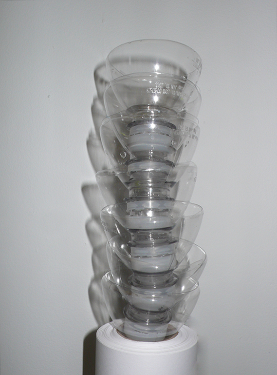 Turmartige Skulptur aus transparenten PET-Schalen, die übereinander gestapelt eine vertikale, leicht gedrehte Form bilden.