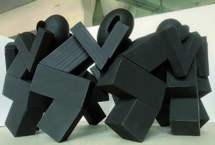 Marcel Peltier – "Unbehagen" Modellserie (ab 2023): Dreidimensionales Modell aus dunklem, matt wirkendem Material auf hellem Untergrund. Mehrere abstrahierte, menschlich anmutende Figuren stehen dicht nebeneinander und sind aus kantigen, blockhaften Volumen zusammengesetzt. Kugelförmige Köpfe ohne Gesichtszüge kontrastieren mit den schweren, verschränkten Körperformen. Die unruhige Stapelung, Überlagerung und Schrägstellung der Elemente erzeugt einen Eindruck von Spannung, Enge und Instabilität und verweist auf ein Gefühl des körperlichen und räumlichen Unbehagens.