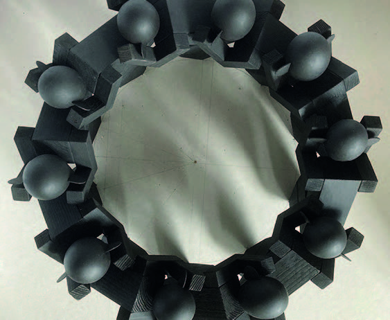 Marcel Peltier – "Unbehagen" Modellserie (ab 2023), Draufsicht: Kreisförmig angeordnete Gruppe abstrahierter, menschlicher Figuren aus dunklem, matt wirkendem Material auf hellem Untergrund. Die kantigen, blockhaften Körper bilden einen geschlossenen Ring, die glatten, eiförmigen Köpfe sind nach innen ausgerichtet. Die strenge Kreisform mit leerem Zentrum verstärkt den Eindruck von Kontrolle, Einengung und kollektivem Druck und verleiht dem Modell eine spannungsvolle, beinahe ritualhafte Wirkung.