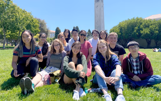 A group of fellows sits on a green lawn.
