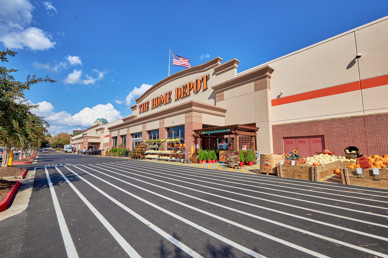 Front exterior of a Home Depot store with display of pumpkins and plants outside under a clear blue sky showing PEC service Surveying.