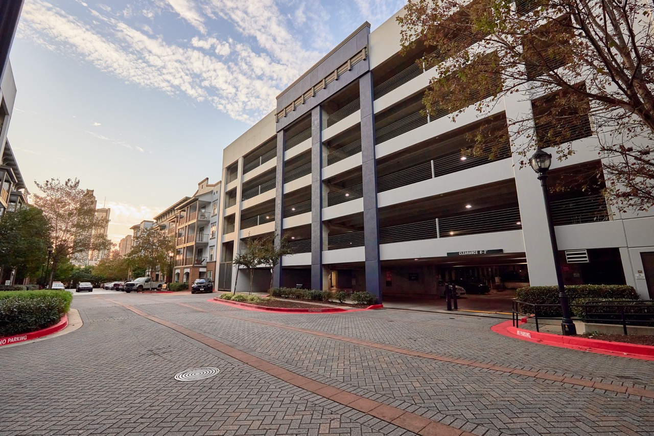 Street view of a multi-story parking garage adjacent to residential buildings under a partly cloudy sky at sunset showing PEC Utility Locate Field service.